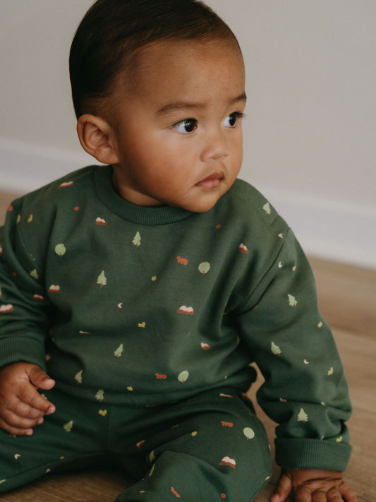 Young child sitting on wooden floor wearing green sweatshirt with nature print Baby Printed Sweatshirt - Mountain View Balsam Baby boy