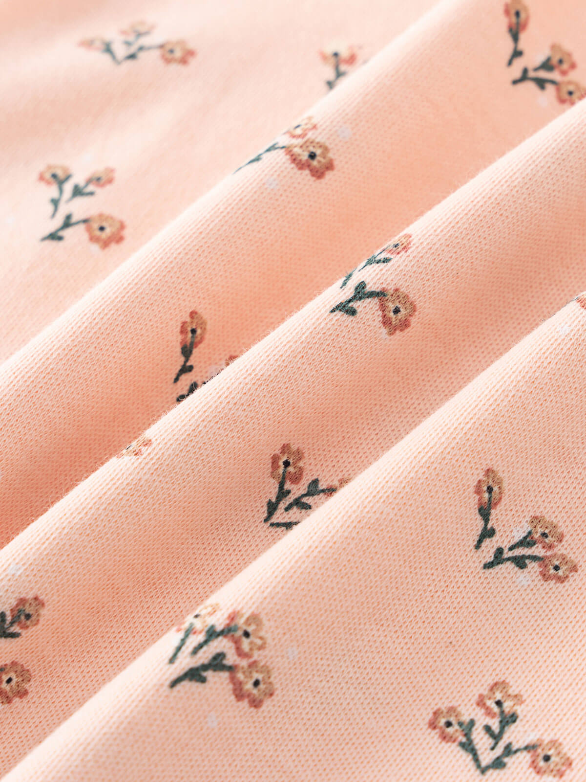 Close-up of peach fabric with small floral pattern printed on it Henley Short Sleeve Bodysuit - Wildflower Bouquet Pink Baby girl