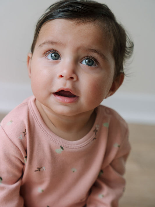 Baby wearing a pink floral patterned long sleeve bodysuit looking upward Long Sleeve Bodysuit - Autumn Harvest Rosehip Baby girl