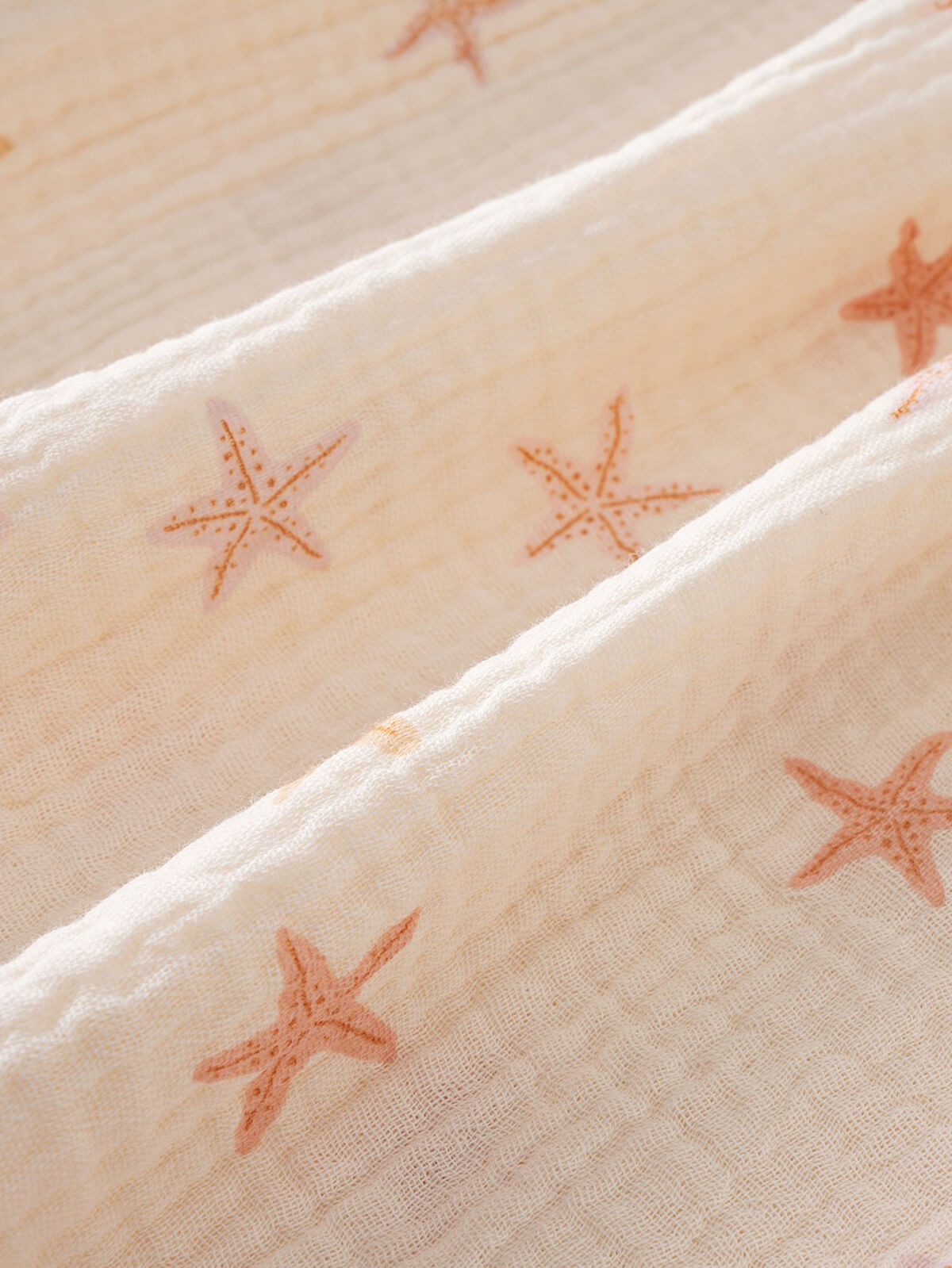Close-up of cream fabric with orange starfish embroidery pattern Amara Dress - Starfish Girls