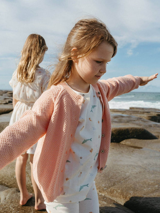 Two young girls on a rocky beach with ocean view