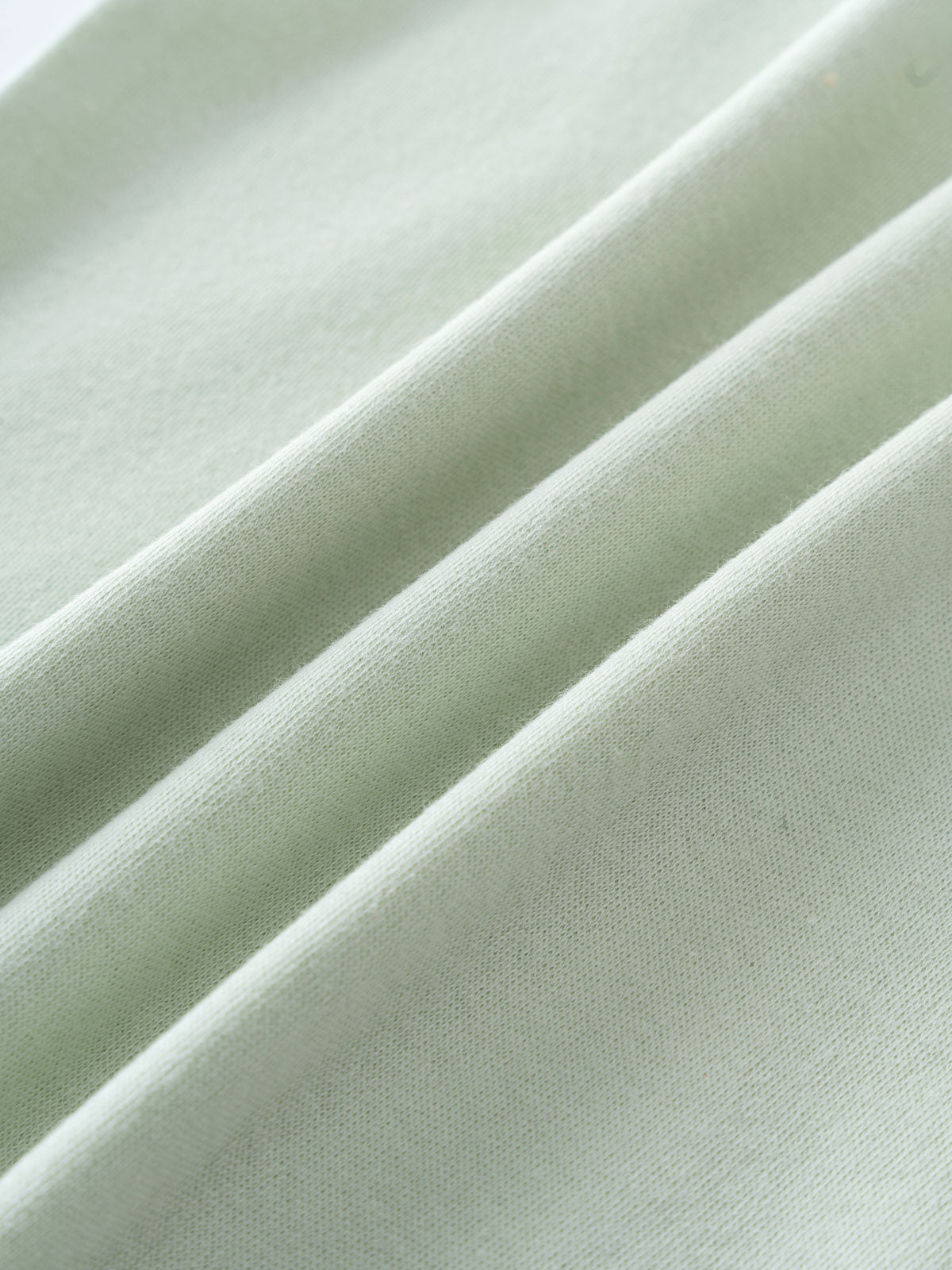 Close-up of soft light green fabric with gentle folds and texture Baby Henley Tee - Matcha Baby boy
