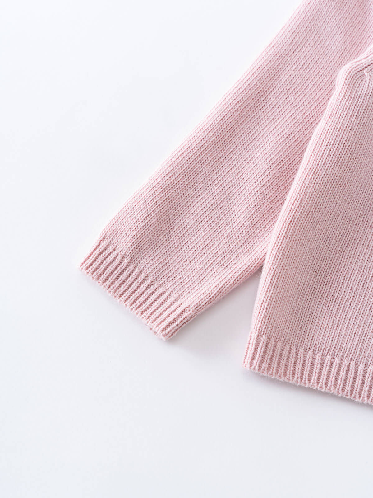 Pink knitted cardigan with ruffled collar on a light gray background