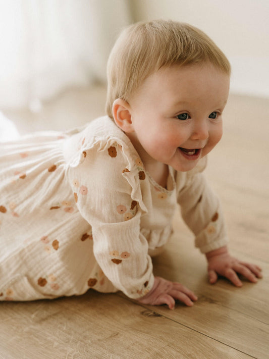 Baby in a white dress with floral patterns on a wooden floor Baby Woven Dress - Autumn Bouquet Ecru Baby girl