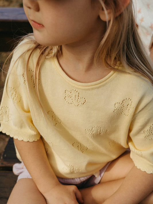 Child wearing a yellow knit sweater with intricate patterns