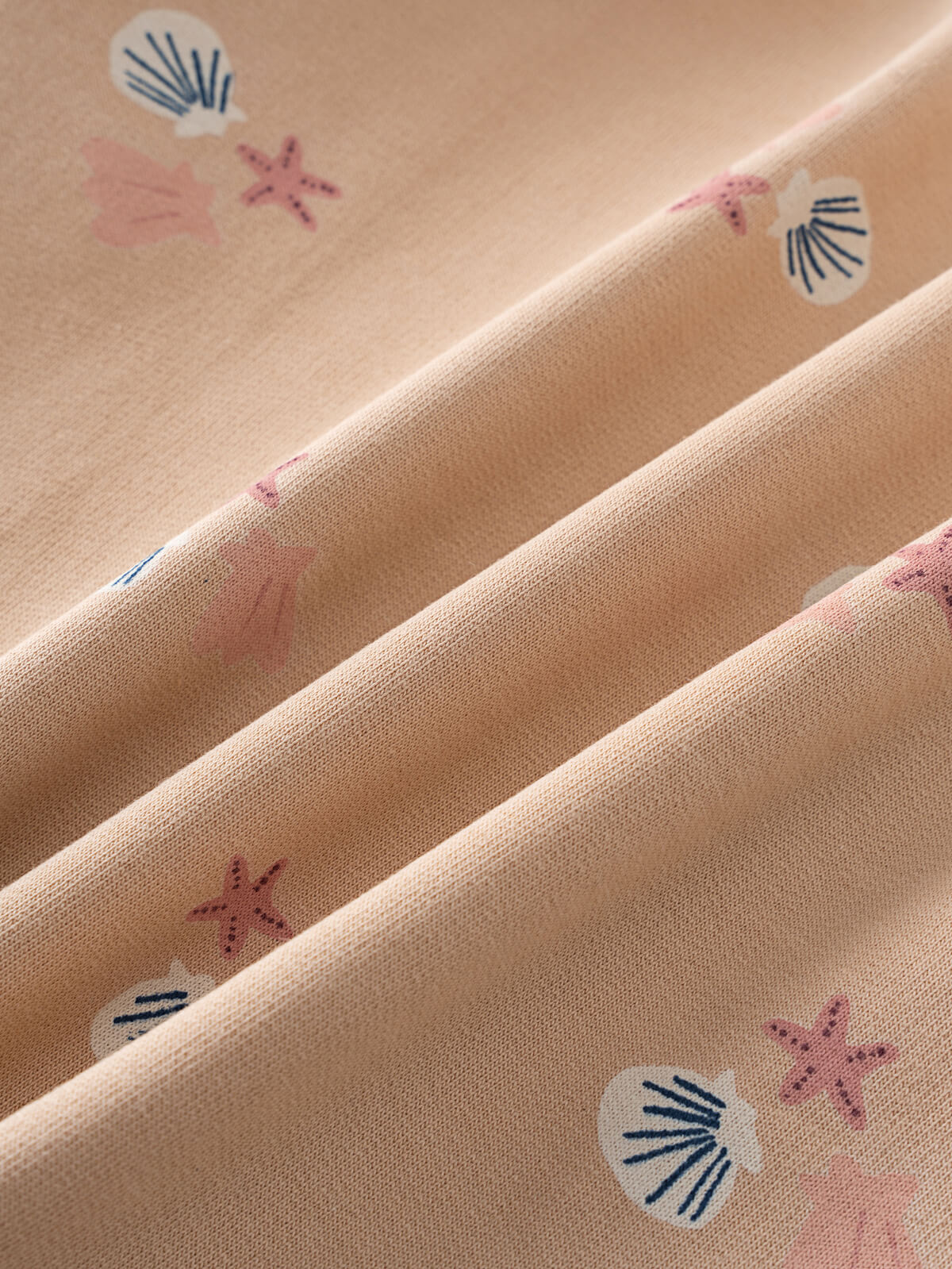 Close-up of peach fabric with small seashell and starfish pattern Evelyn Sweatshirt - Sandy Shells Girls
