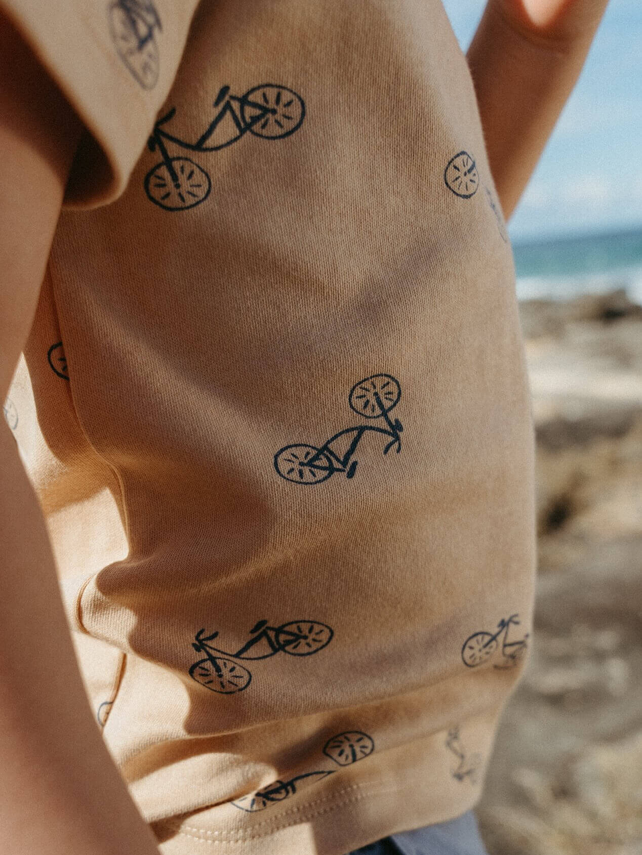 Beige fabric with black bicycle patterns, blurred beach background Ezra Short Sleeve Tee Shirt - Bikes Boys