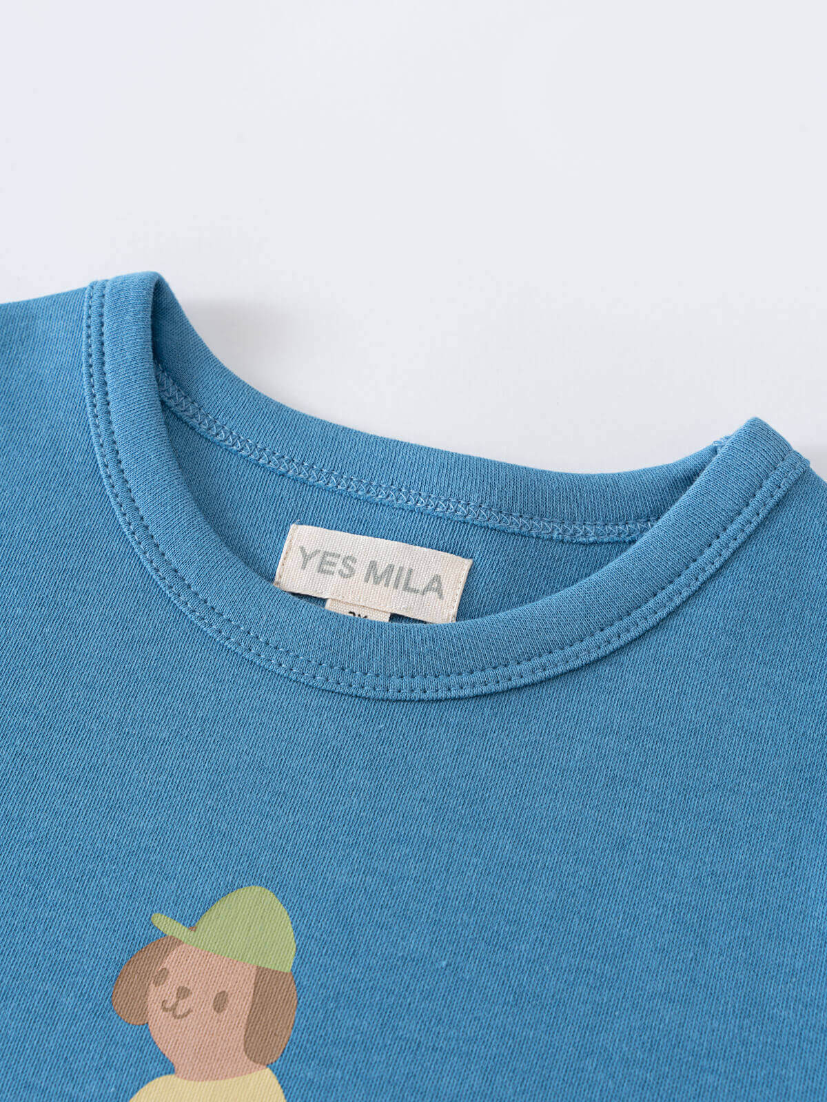 Close-up of a blue t-shirt collar with a small printed graphic below feature print Short Sleeve Tee - Milo Biking Boys