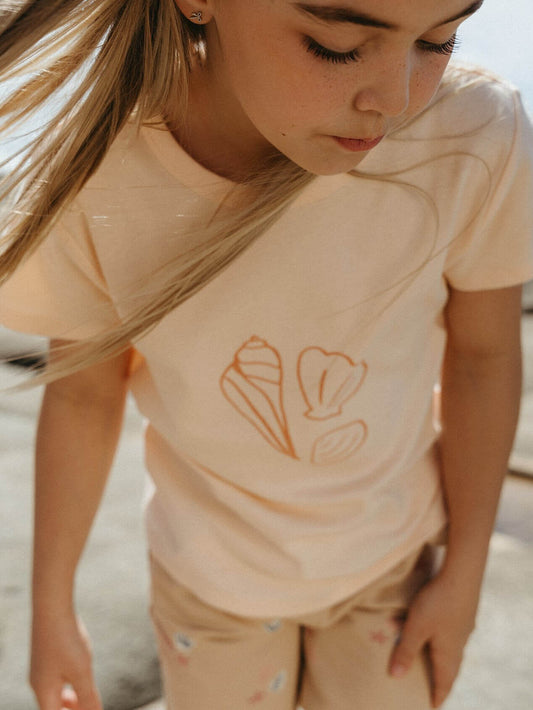 Young girl wearing a peach colored shirt with shell graphic embroidery Hazel Short Sleeve Tee Shirt - Shells Girls
