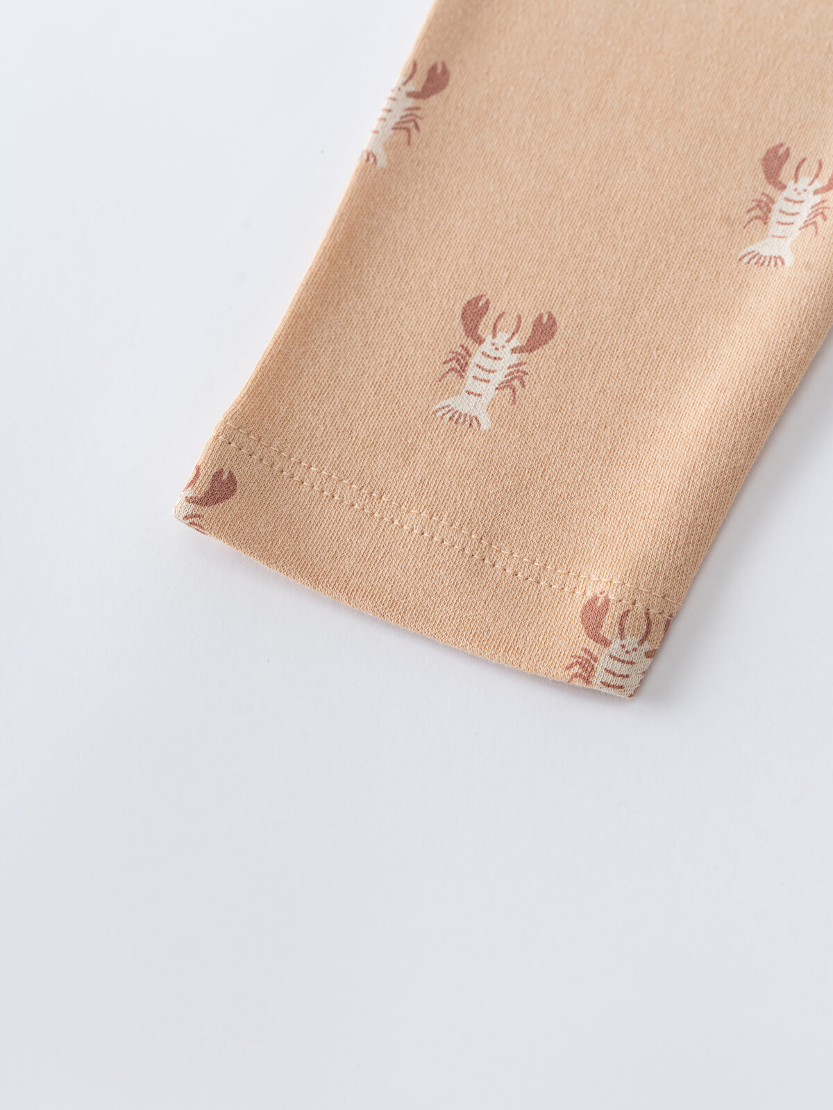 Close-up of peach fabric with red lobster print pattern Heath Leggings - Charlie's Crew Baby boy