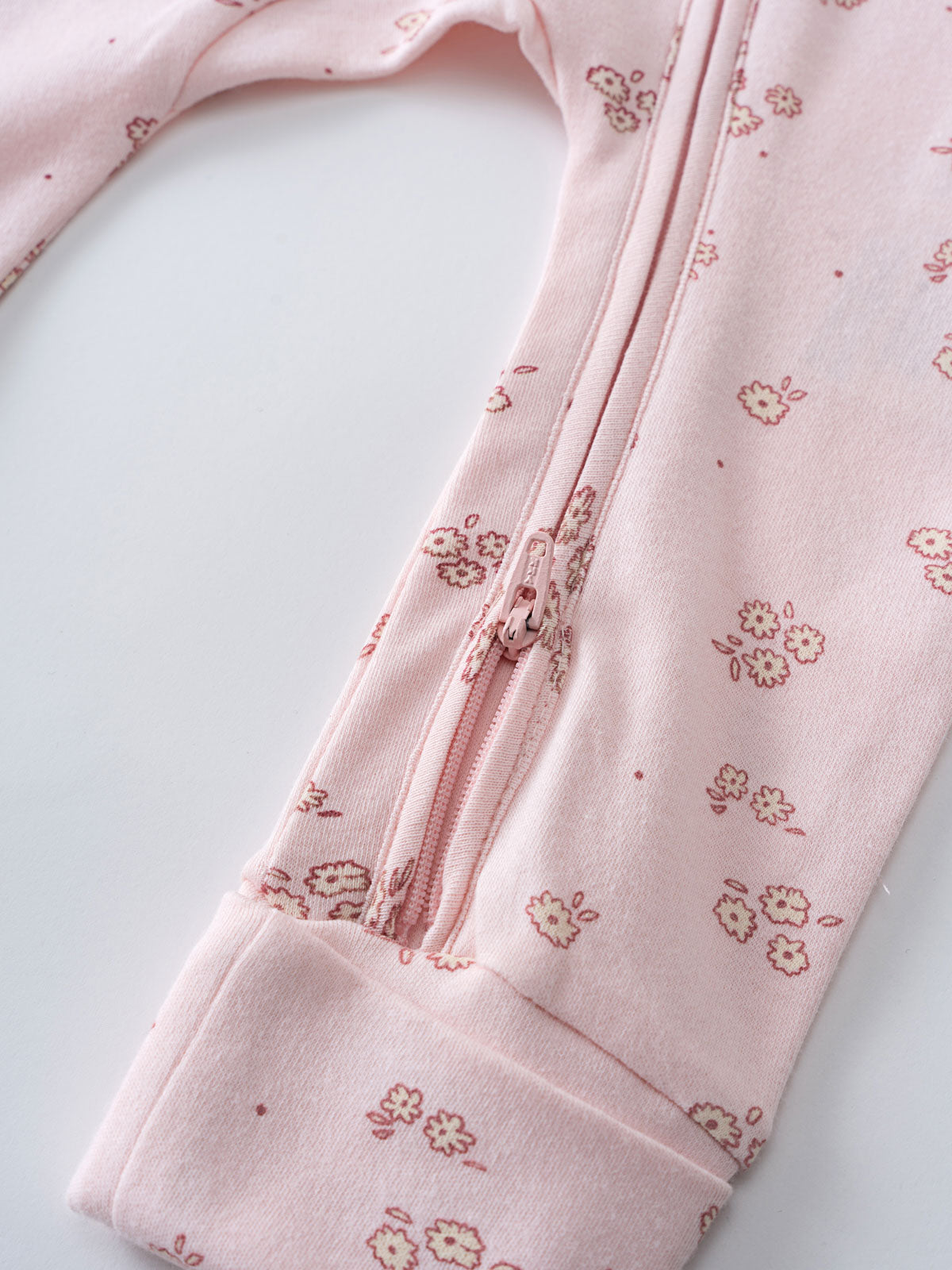 Close-up of a pink floral patterned baby garment with zipper detail Ivy Long Sleeve One Piece - Daisy Chain Baby girl