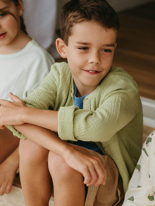 Young boy in a green shirt sitting on the floor with a blurred background