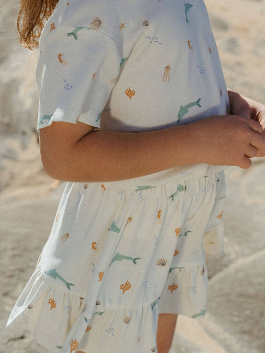Girl wearing a light blue dress with animal prints on a sandy background