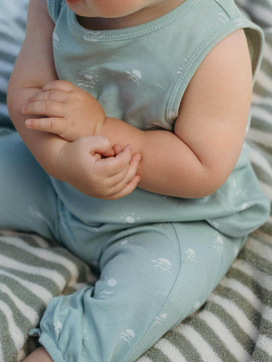 Baby in light blue outfit sitting on a striped surface