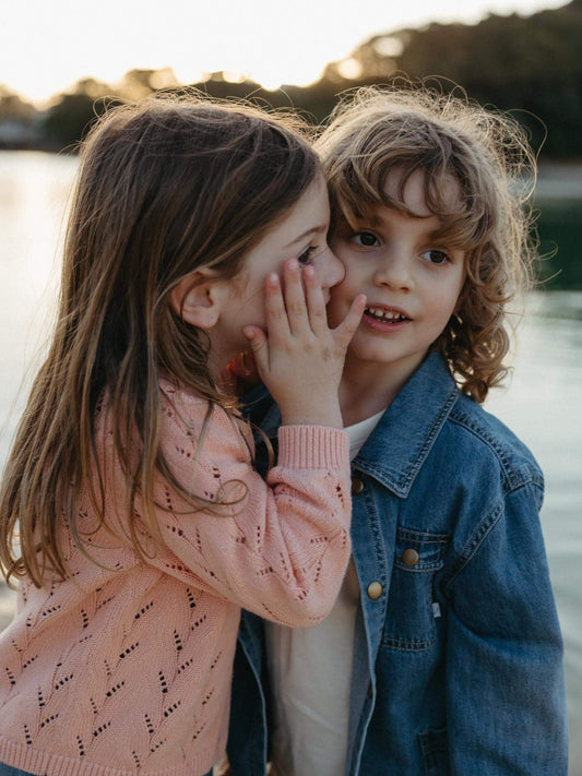 Girl playing with a boy at the beach wearing a pink cardigan
