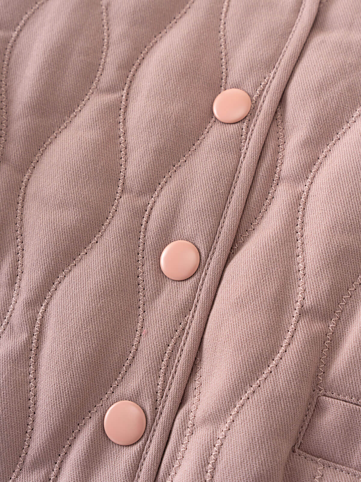 Close-up of a quilted jacket with pink buttons on a light brown background Quilted Jacket - Blush Baby girl