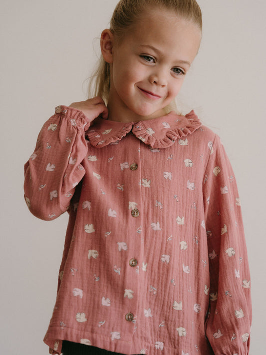 Young girl wearing a pink patterned button-up blouse with ruffled collar Ruffle Woven Blouse - Bird And Blossom Rosehip Girls