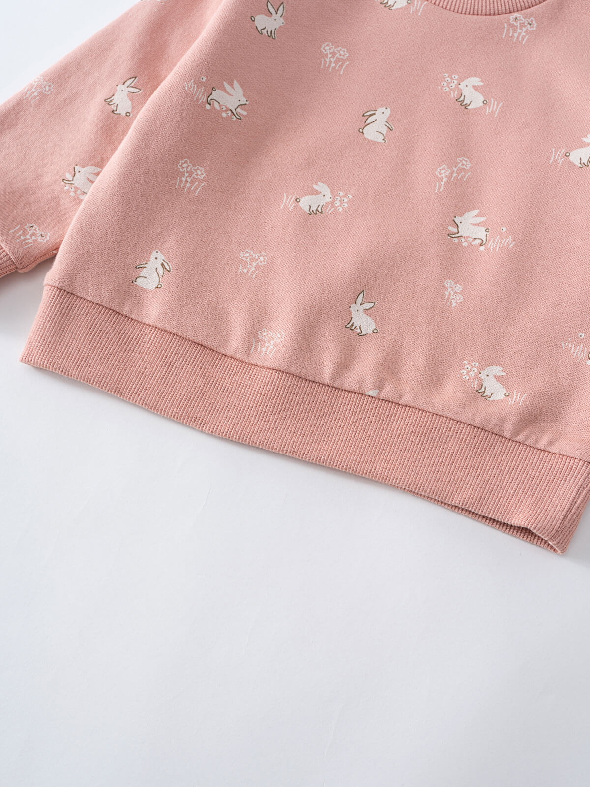 Close-up of pink sweatshirt hem with white bunny and flower print Baby Printed Sweatshirt - Meadow Friends Blush Baby girl
