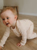 Baby crawling on wooden floor wearing cream ribbed long sleeve outfit Ribbed Long Sleeve One Piece - Clay Baby girl
