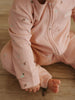 Baby wearing a pink printed onesie with zipper sitting on wooden floor Printed Long Sleeve One Piece - Autumn Harvest Rosehip Baby girl