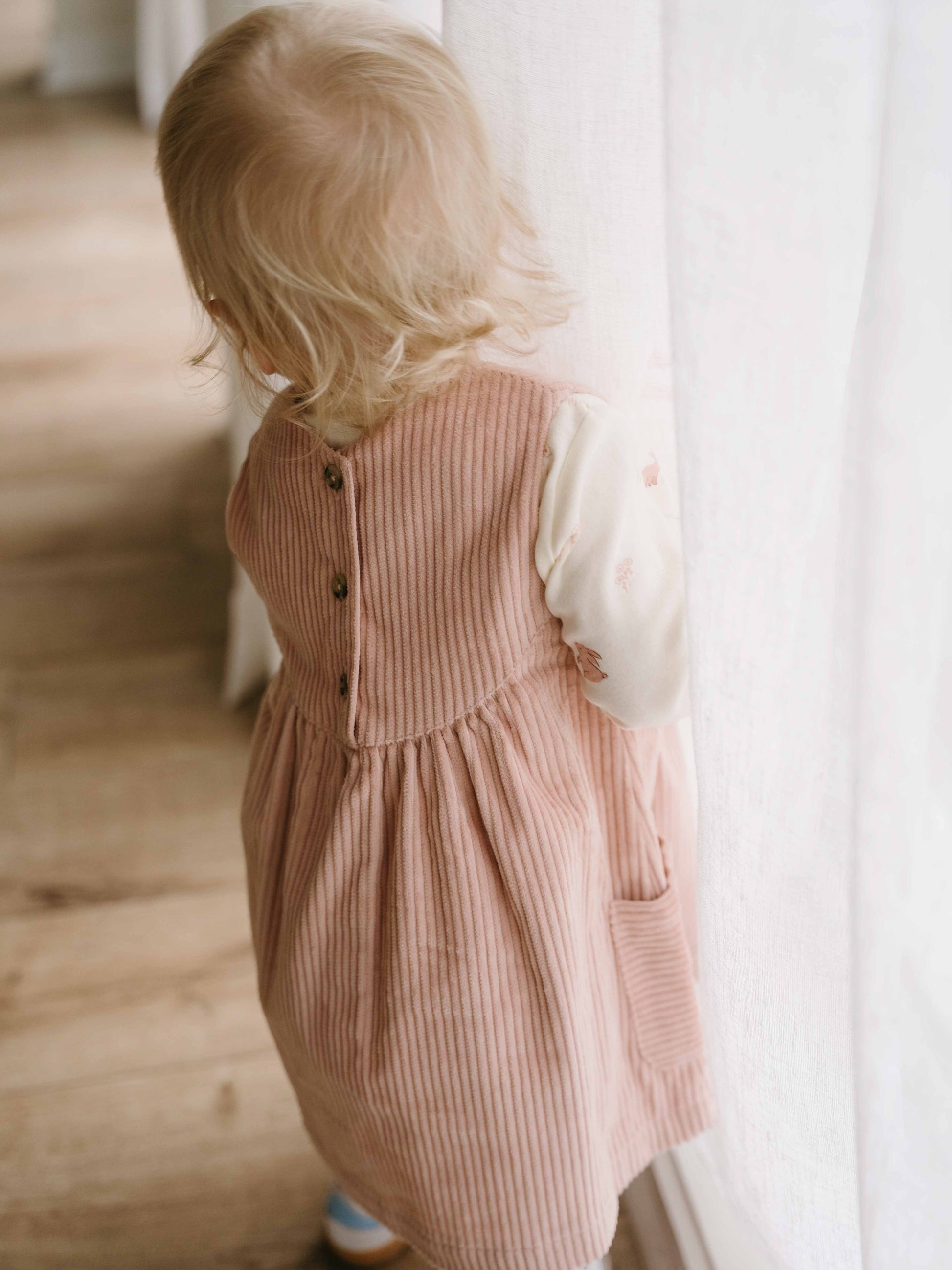 Child wearing a pink corduroy dress standing indoors with a neutral background Baby Corduroy Dress - Blush Baby girl