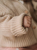 Close-up of a child's hand in a beige knitted sweater with a blurred background Ribbed Hooded Cardigan - Clay Baby boy