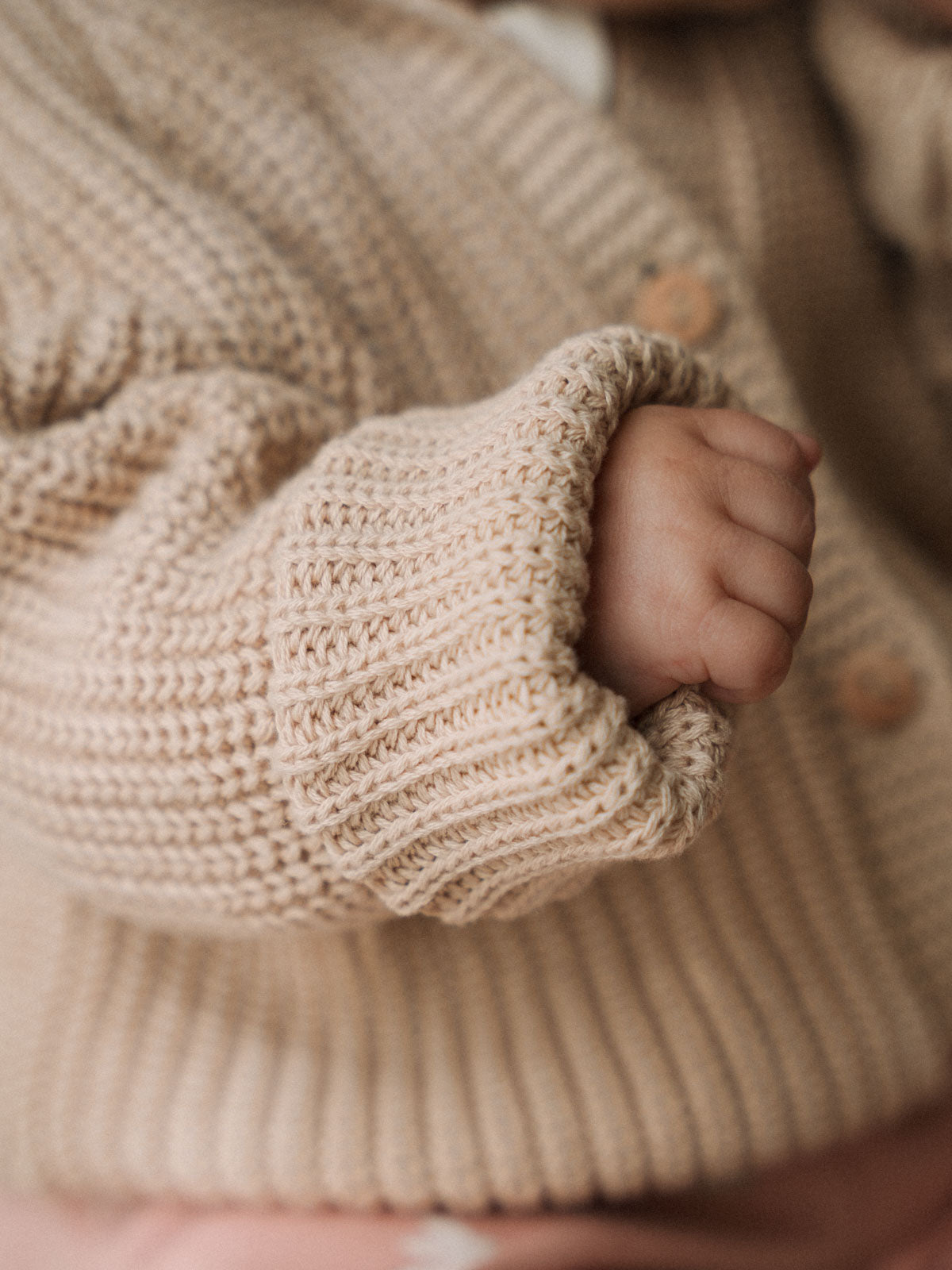 Close-up of a child's hand in a beige knitted sweater with a blurred background Ribbed Hooded Cardigan - Clay Baby boy