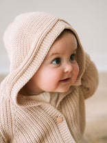Baby wearing a beige knitted hoodie with a hood, looking to the side. Ribbed Hooded Cardigan - Clay Baby boy