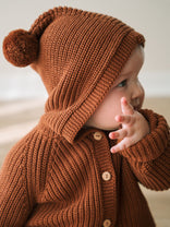 Baby wearing a rust-colored ribbed knit cardigan and matching hooded hat with pompom Ribbed Hooded Cardigan - Russet Baby boy