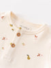 Close-up of cream-colored baby bodysuit with fruit pattern and wooden buttons Henley Short Sleeve Bodysuit - Autumn Harvest Ecru Baby girl