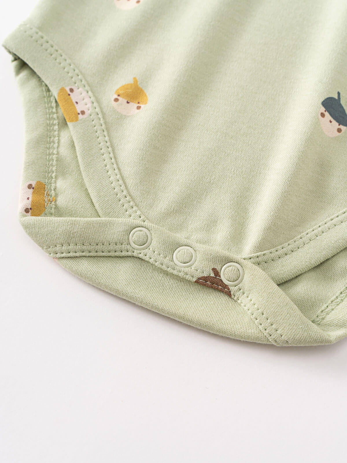 Close-up of a pale green baby bodysuit with snap buttons and small acorn prints Henley Short Sleeve Bodysuit - Little Acorn Sage Baby boy
