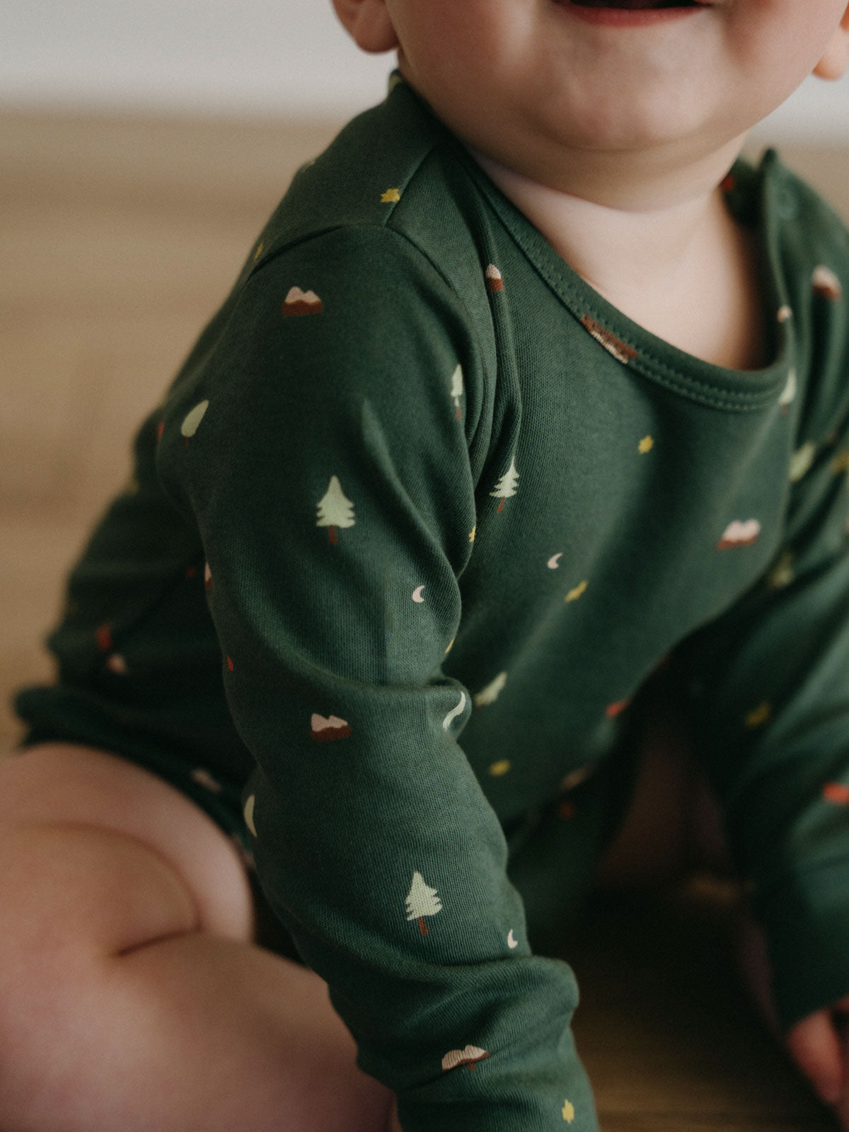 Baby wearing dark green bodysuit with small tree and nature print pattern Long Sleeve Bodysuit - Mountain View Balsam Baby boy
