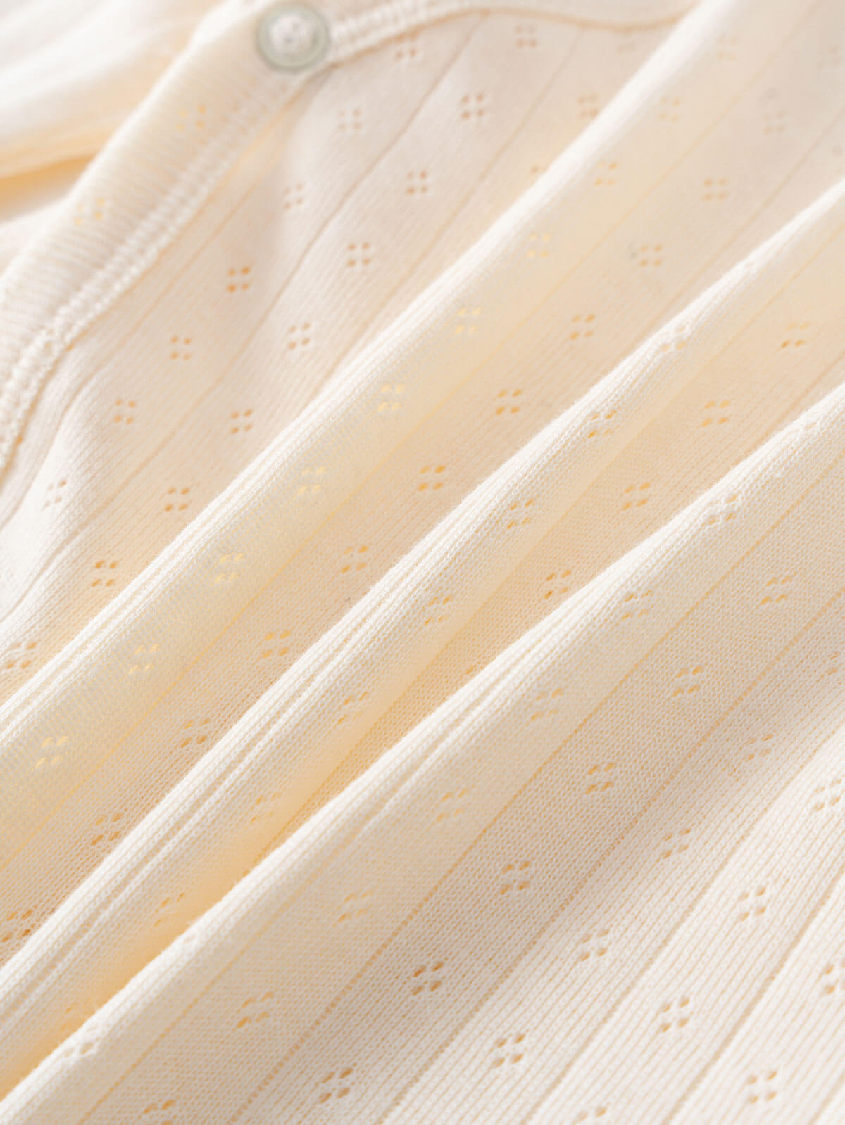 Close-up of cream-colored fabric with pointelle detail and button fastening Pointelle Crossover Bodysuit - Ecru Baby boy