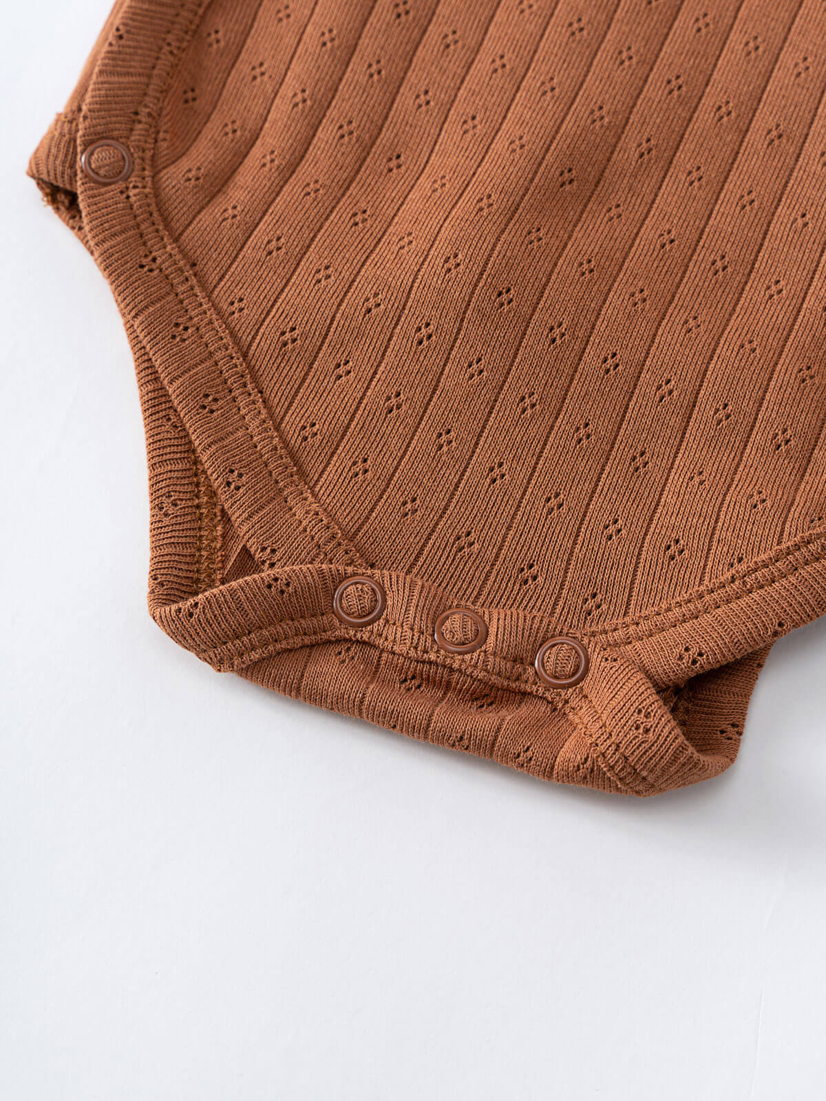 Close-up of rust-colored knit baby bodysuit with snap closures and textured pattern Pointelle Crossover Bodysuit - Russet Baby boy