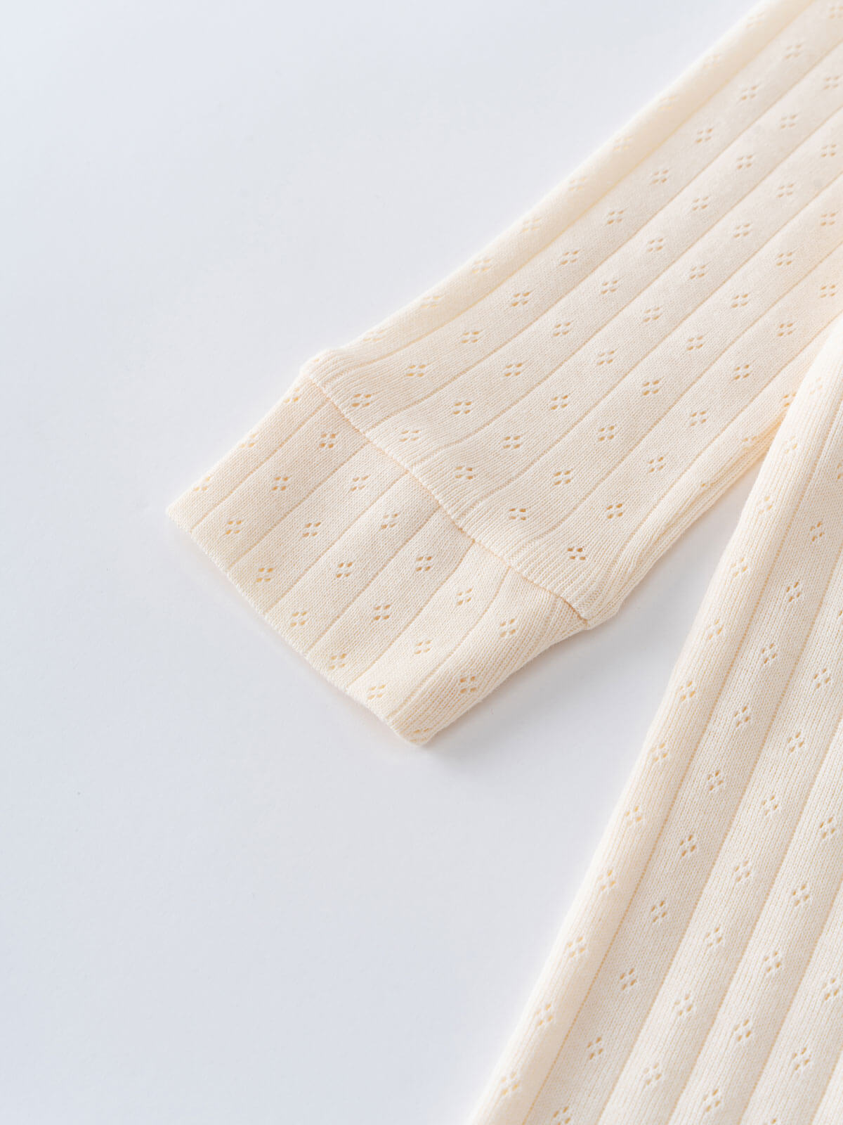 Close-up of a textured beige fabric on a light gray background Pointelle Long Sleeve One Piece - Ecru Baby boy