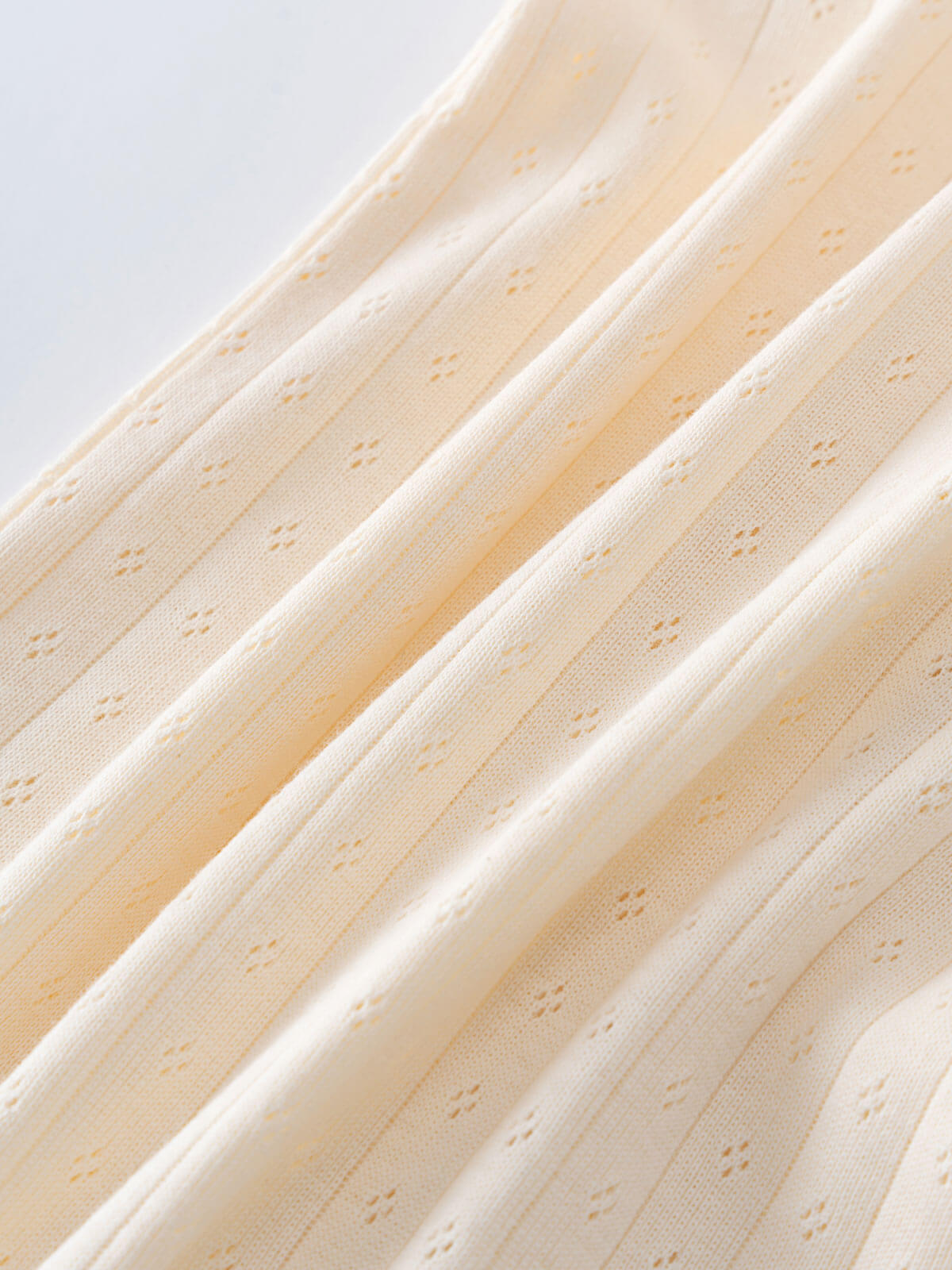 Close-up of beige fabric with a subtle pattern on a light gray background Pointelle Long Sleeve One Piece - Ecru Baby boy