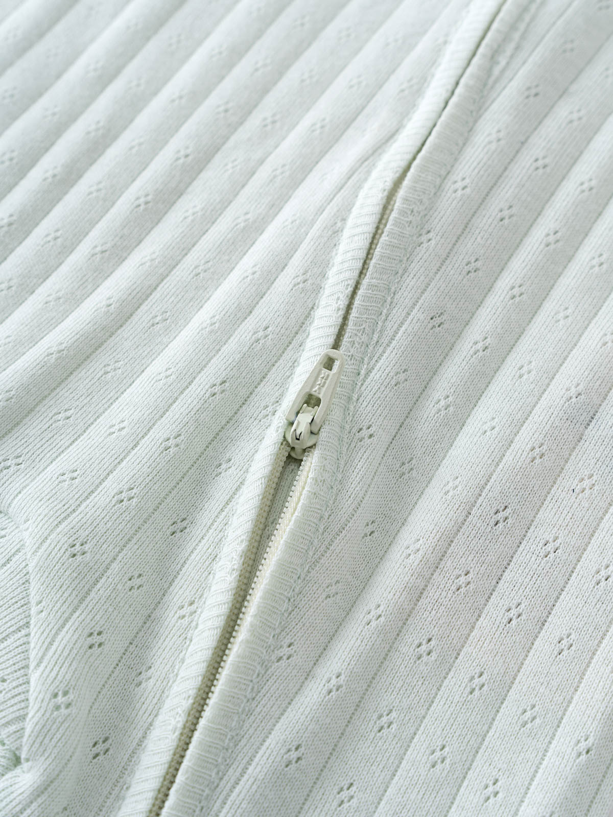 Close-up of a textured fabric with a zipper running through it. Pointelle Long Sleeve One Piece - Sea Foam Baby boy