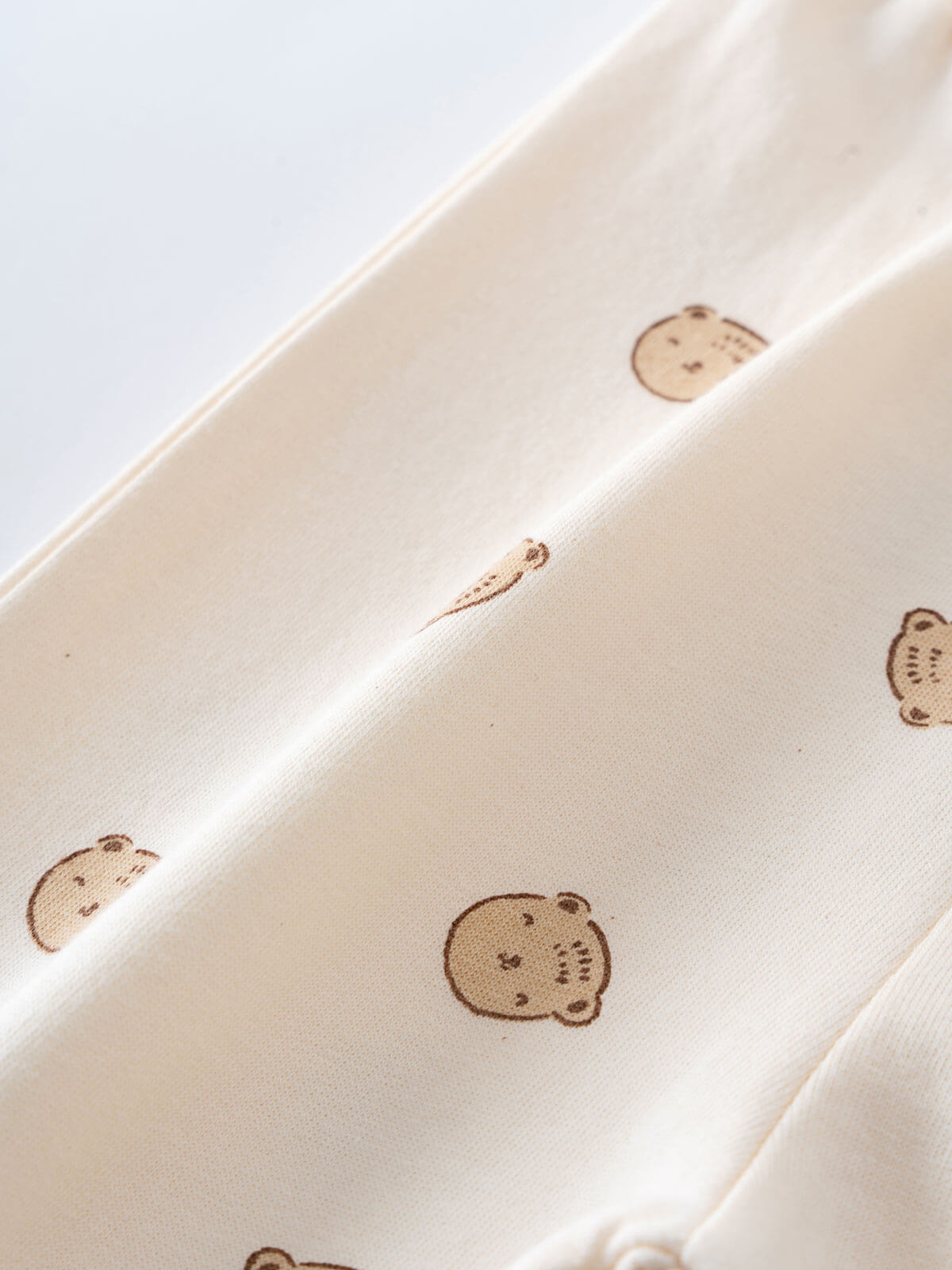 Cream fabric with small brown bear print pattern close-up view Printed Sweatpants - Cosy Bear Ecru Baby boy