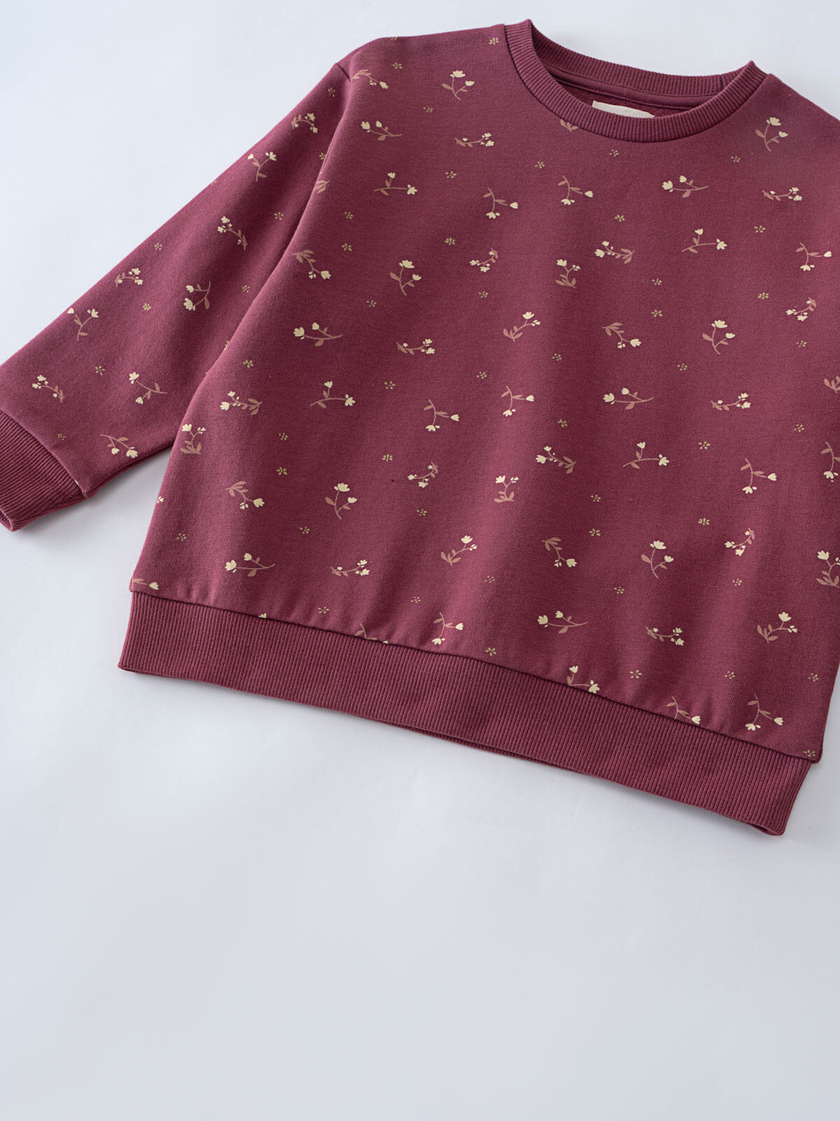 Burgundy sweatshirt with small floral print pattern laid flat on white surface Printed Sweatshirt - Wild Meadow Plum Jam Girls