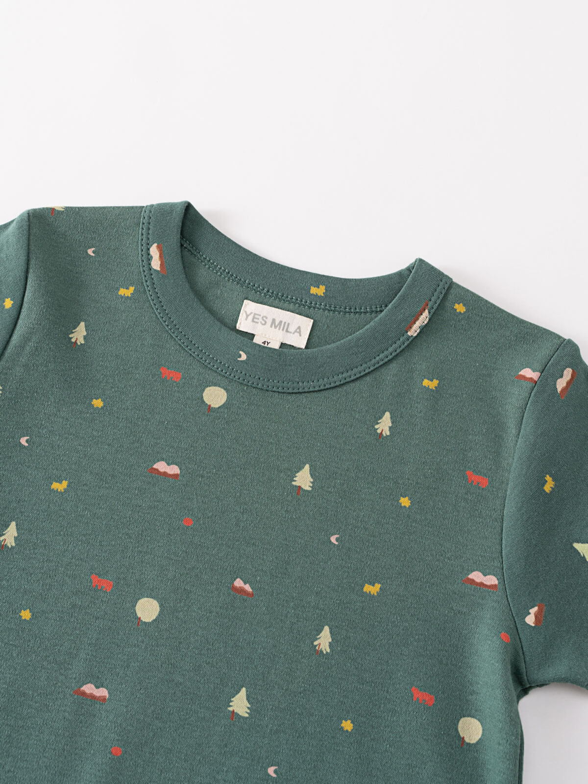 Close-up of a green tee with small printed patterns including trees and stars Baby Printed Short Sleeve Tee - Mountain View Ecru Baby boy
