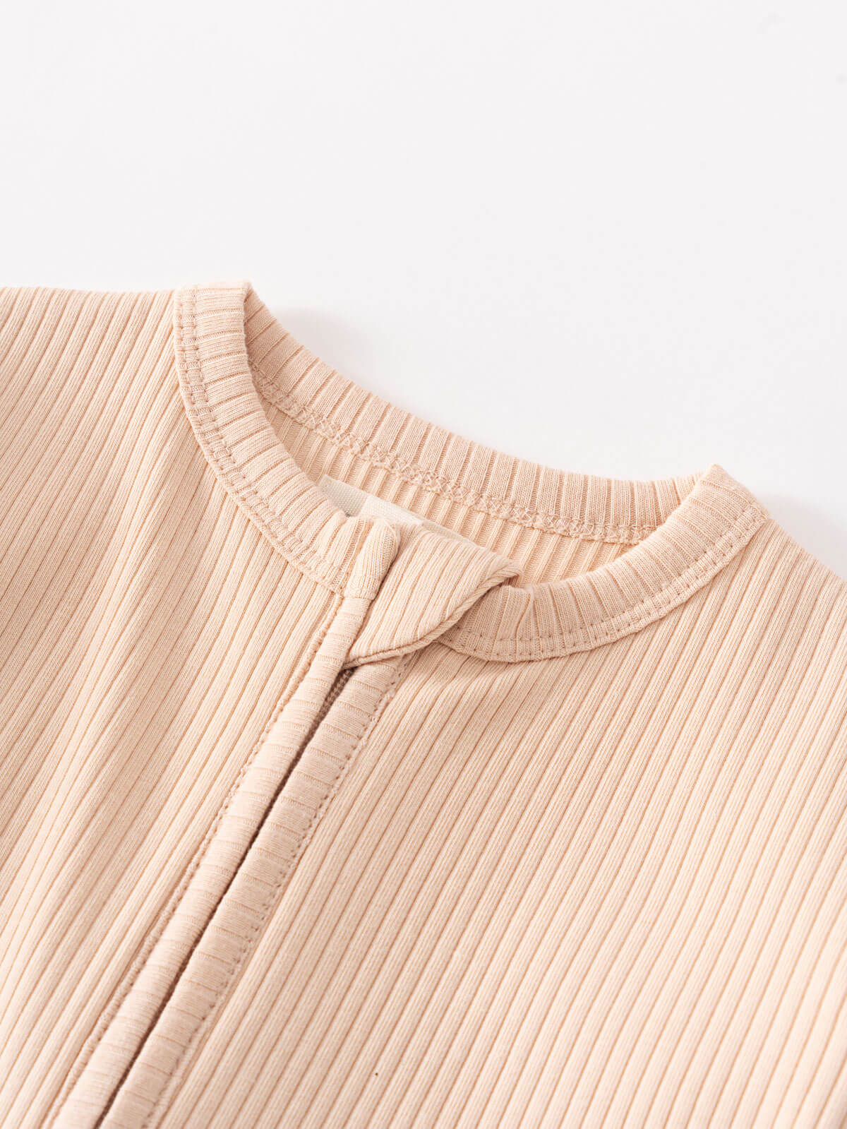Close-up of a beige ribbed knit garment with button placket detail Ribbed Long Sleeve One Piece - Clay Baby girl