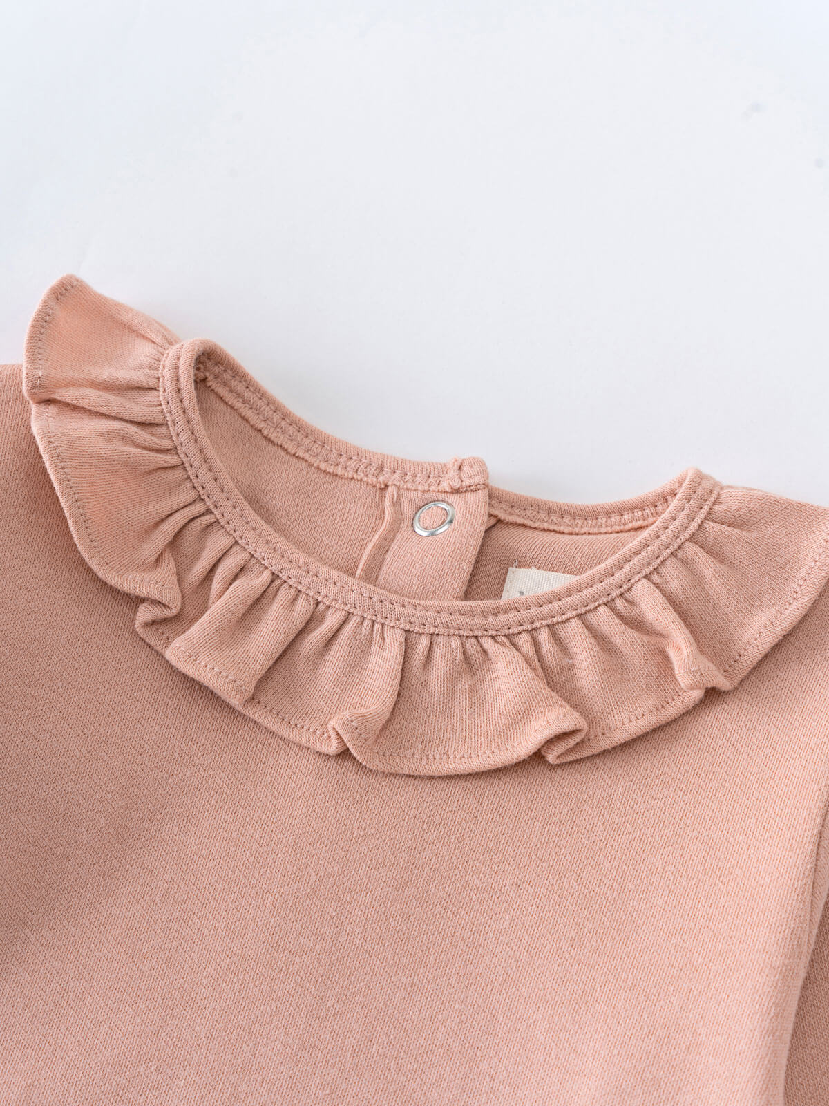 Close-up of a peach-colored bodysuit with ruffled collar and snap closure Ruffle Long Sleeve Bodysuit - Blush Baby girl