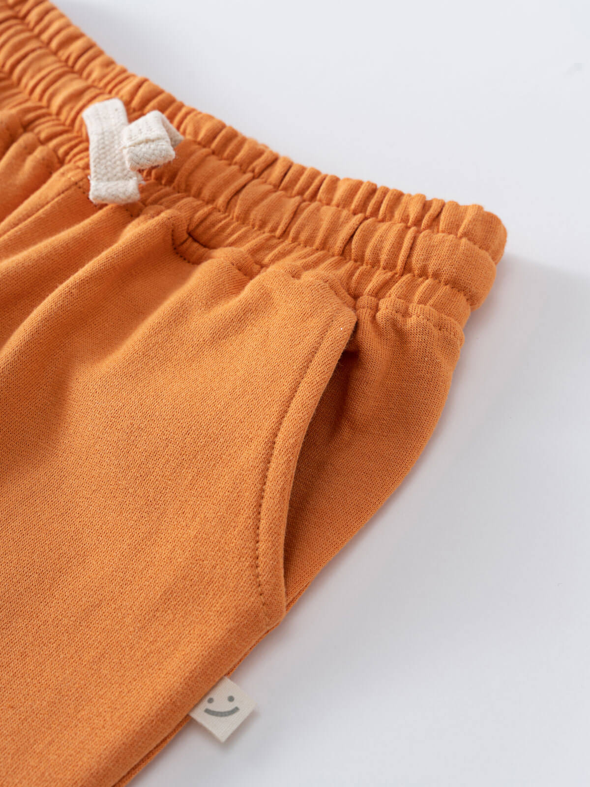 Close-up of orange sweatpants waistband with white drawstring and pocket detail Sweatpants - Pumpkin Boys