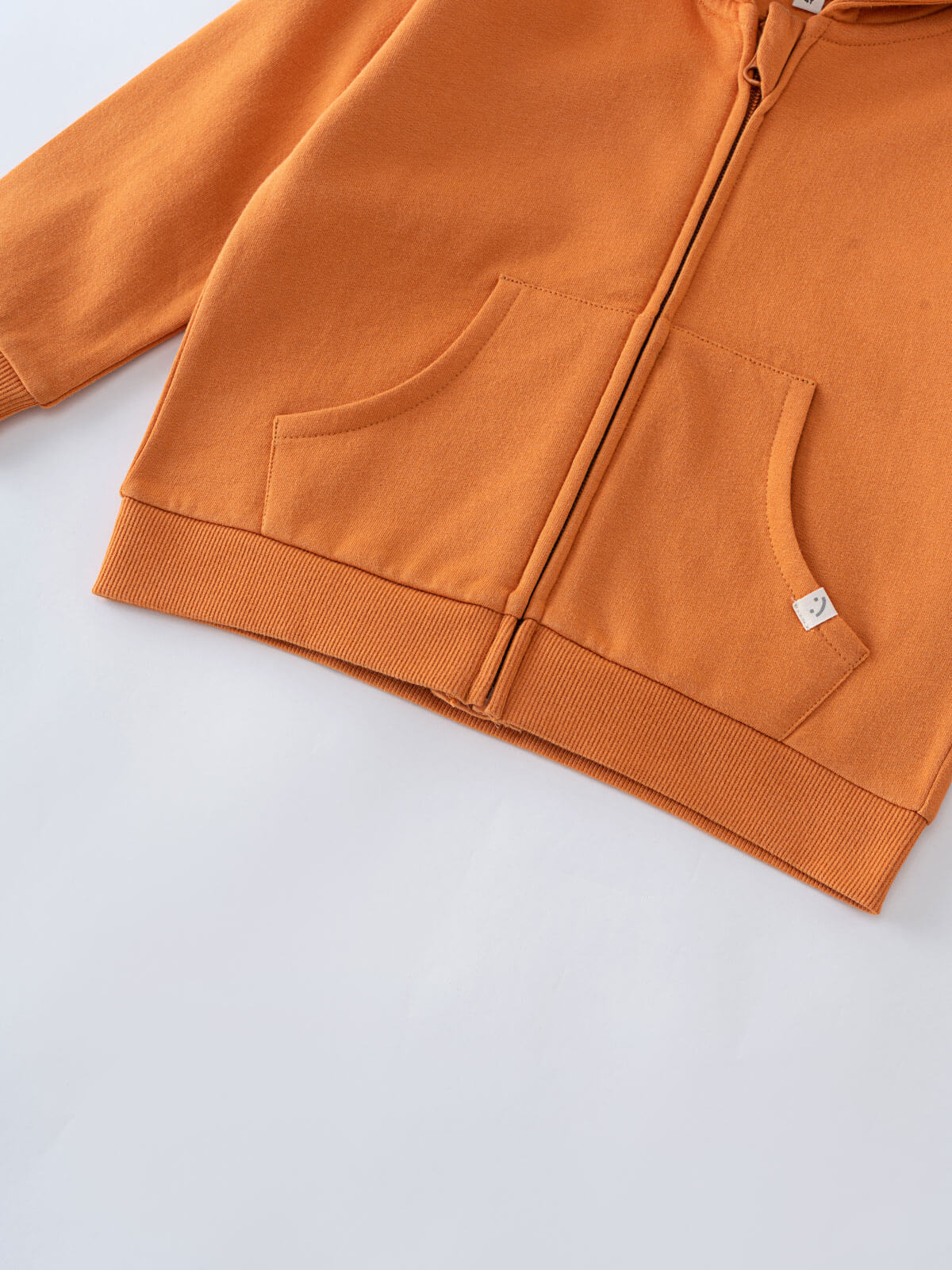 Close-up of orange hoodie showing front pockets and ribbed hem with zipper Zip Hoodie - Pumpkin Boys
