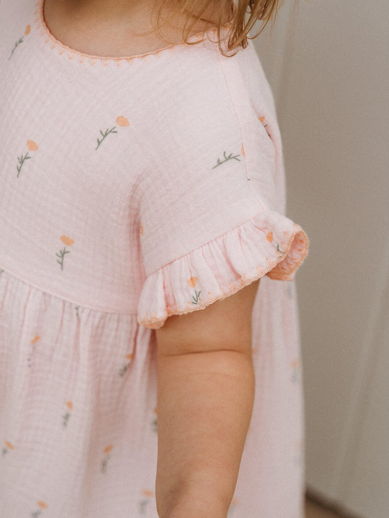 Child wearing a light pink dress with floral embroidery on a neutral background Amara Dress - Poppy Field Girls