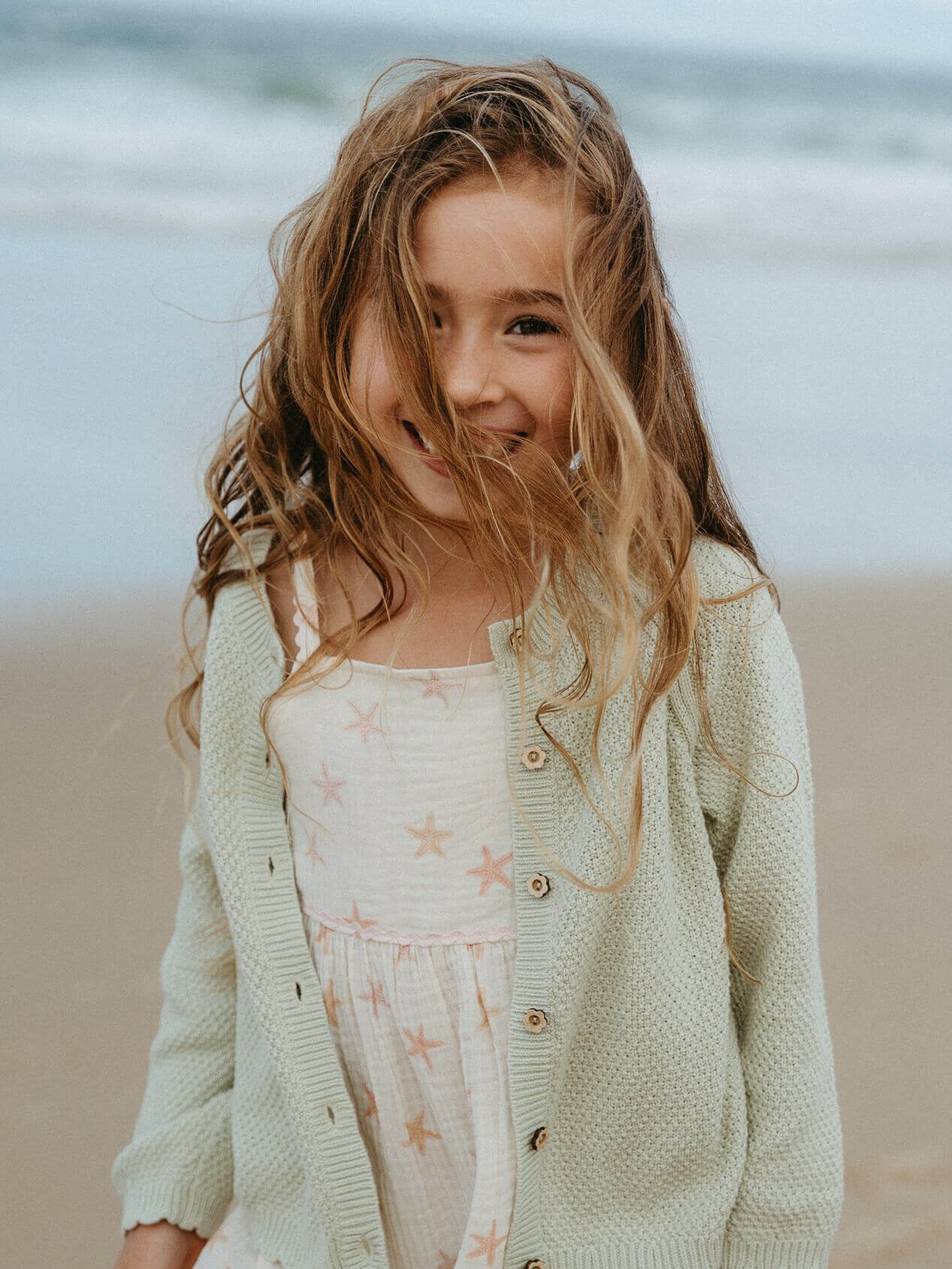 Young girl standing on a beach with ocean in the background
