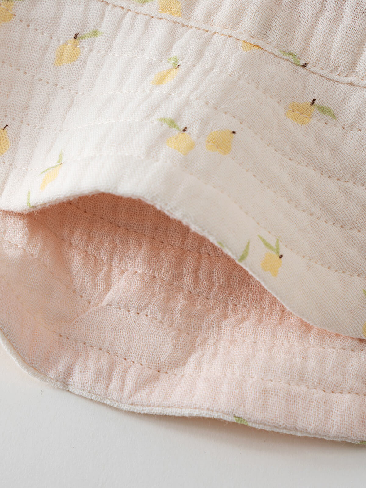 Close-up of light fabric with yellow lemon print and visible stitching baby Bucket Hat - Lemons Baby girl