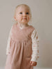 Young child wearing a pink dress over a white shirt with floral patterns against a plain background Baby Corduroy Dress - Blush Baby girl
