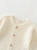 Close-up of a cream-colored knitted cotton cardigan with button details on a light gray background Baby Cotton Cardigan - Ecru Baby boy