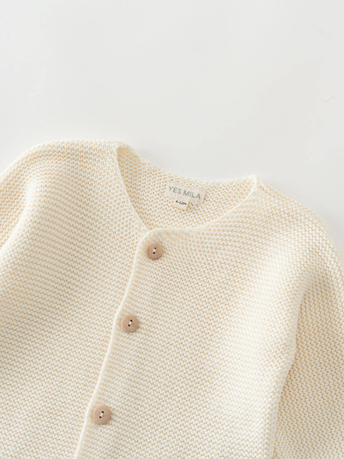 Close-up of a cream-colored knitted cotton cardigan with button details on a light gray background Baby Cotton Cardigan - Ecru Baby boy